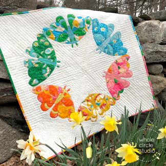 Full photo of a modern quilt of 6 moths in a circle with a daffodil in the foreground