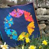 Full photo of a modern quilt of 6 moths in a circle with daffodils in the foreground
