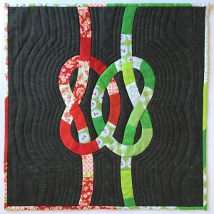 quilt with red and green knots intertwined on a dark gray background