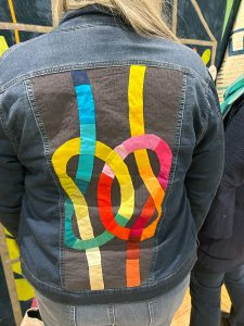 colorful quilt block knots intertwined on the back of a jean jacket