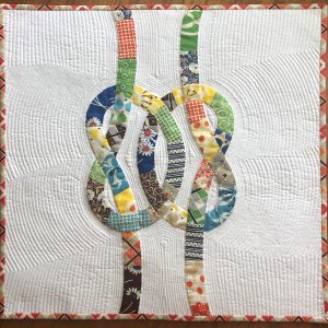 quilt with colorful knots intertwined on a white background