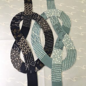 quilt block with dark blue and light blue knots intertwined on a light gray background