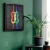 framed quilt of two colorful knots interlocking in a room next to a window and a plant