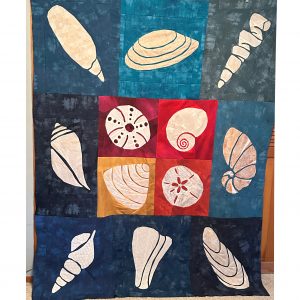 Blue, red, yellow, wine, and cream seashell quilt made with the Shoreline Shells Block of the Month pattern.