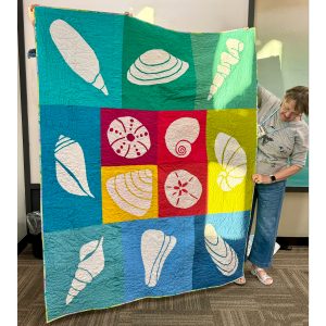 Rainbow seashell quilt made from the Shoreline Shells quilt pattern by Whole Circle Studio.