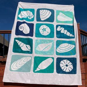 Turquoise, blue, and sand seashell quilt made with the Shoreline Shells quilt pattern.