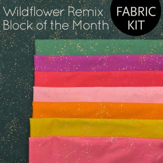 stack of colorful fabrics on a forest green fabric