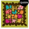 Colorful Wildflower Remix Queen quilt showing large floral quilt blocks on a brown background with a green border