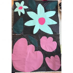 two flower quilt blocks with bright pastel colors on a textured black and gray background