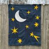 yellow, white, and navy blue moon and star quilt hanging on a fence