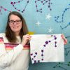 woman holding a paper pieced scorpio constellation quilt block