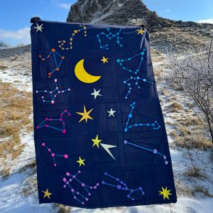 modern star and moon quilt being held up in nature