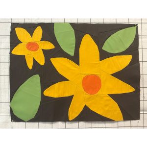 quilt block of large yellow and orange flowers and leaves on a navy background