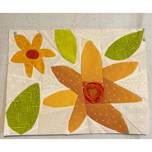scrappy quilt block of large yellow and orange flowers and leaves on a light white and cream background