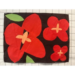 Wildflower quilt block with geometric shapes made with red, pink, green, and black fabrics