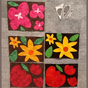 5 flower quilt blocks pinned to a wall
