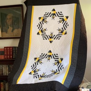 Twin size quilt made from repeating bee blocks arranged in a two circular geometric layout.