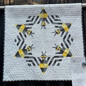 Modern quilt featuring large stylized bees in a graphic contemporary design.