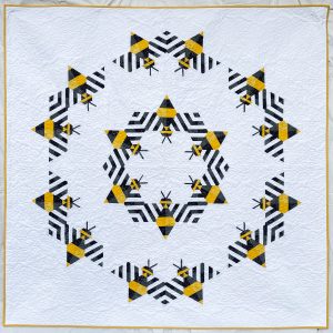 Large quilt made from repeating bee blocks arranged in a modern circular geometric layout.