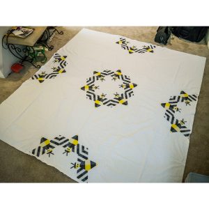 Large quilt made from repeating bee blocks arranged in a modern geometric layout.