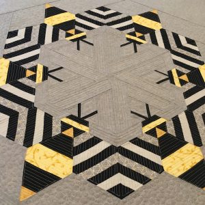 Close up of odern wall quilt with large pieced bees made with yellow, white, black, and gray fabrics