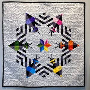 Colorful bee-themed quilt featuring modern pieced bees and geometric shapes.