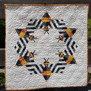 finished bee quilt with bees arranged in a circle and flower motif quilting