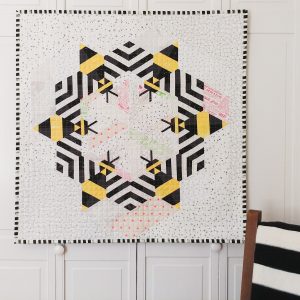 bee-themed quilt with 6 bees in a circle and a black and white background and binding