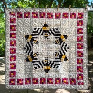 Modern bee quilt with colorful border hanging on a clothesline