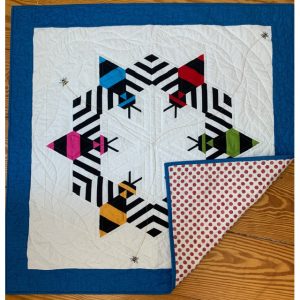 colorful quilt featuring 6 bees and a blue border with the corner turned over to show the back