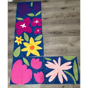 rows of colorful flower quilt blocks on a navy background on a floor