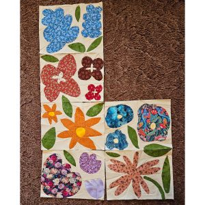 colorful flower quilt blocks made with fabric scraps sitting on a brown carpet