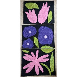 Pink, purple, and green flower quilt blocks displayed on a design wall during the quilting process.