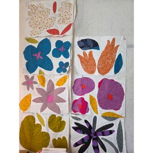 A collection of colorful flower quilt blocks laid out on a design wall to plan the quilt design.