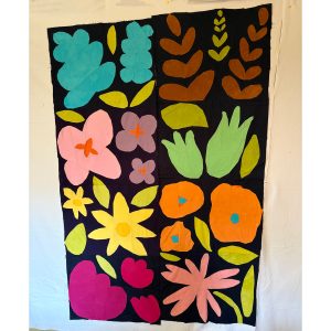 Flower quilt blocks in various colors arranged together on a design wall as part of a quilt in progress.