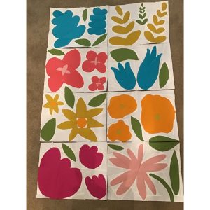 Quilt flower blocks in progress made with colorful fabric arranged on the floor.